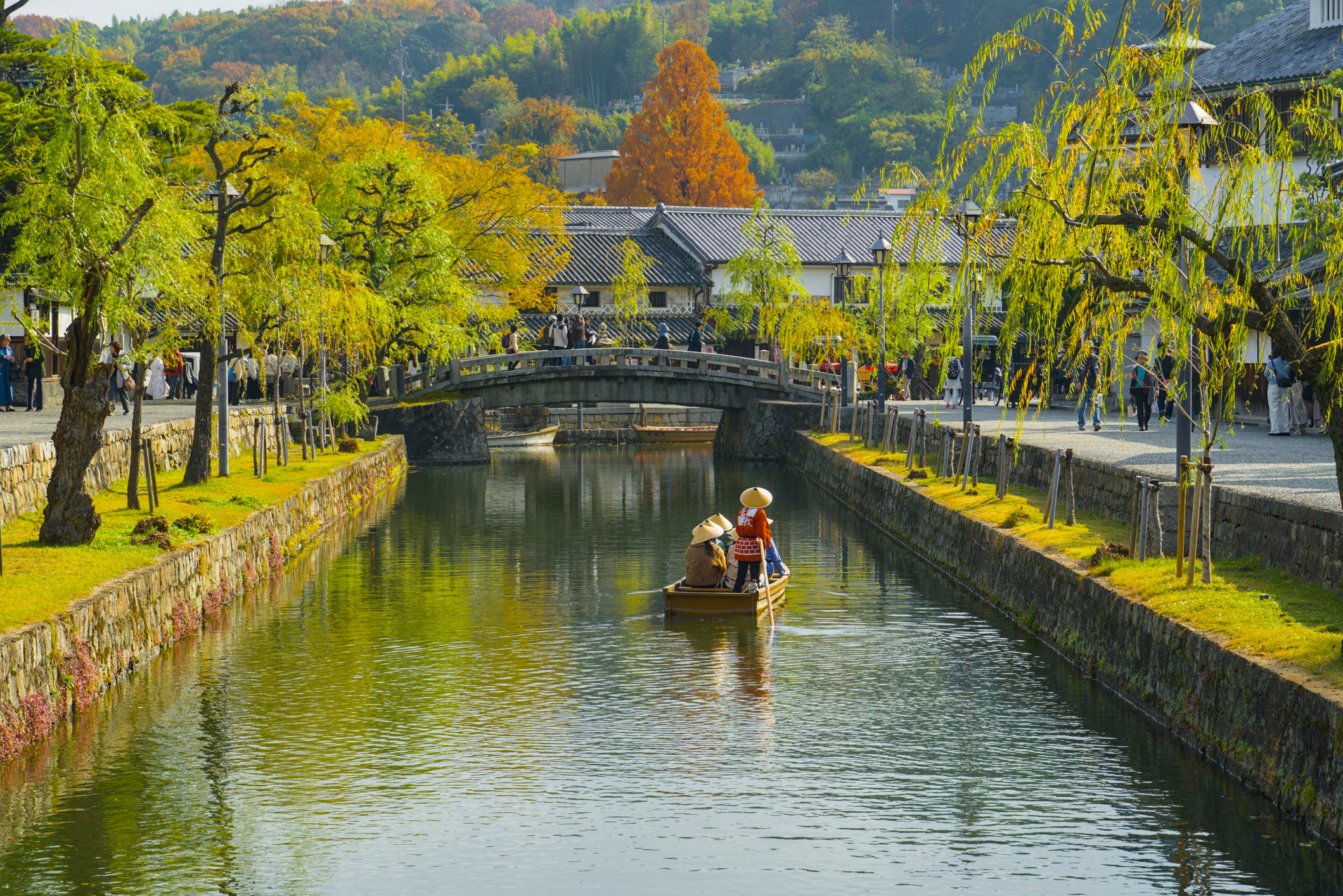 Canal Lined Scenery Of Kurashiki Bikan Historical Quarter With A Sightseeing Boat Gliding Along The Water