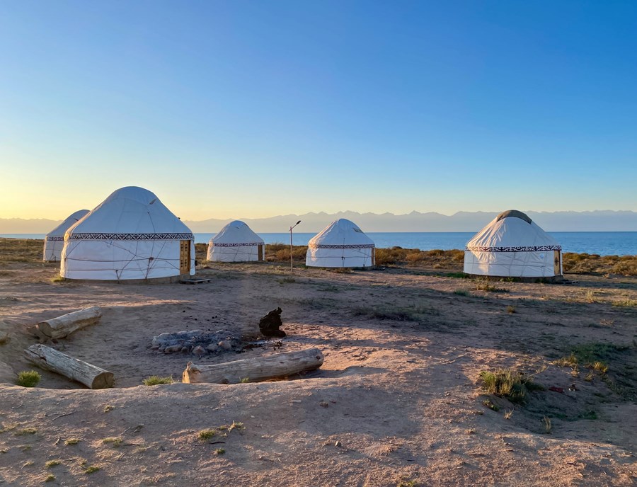 Traditional Yurts On A Sandy Beach At Lake Issyk Kul, With Tian Shan Mountains In The Background At Sunset, Kyrgyzstan