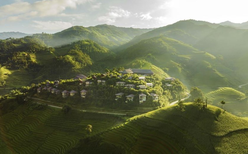 Aerial view of Garrya Mu Cang Chai Resort surrounded by lush rice terraces in northern Vietnam.