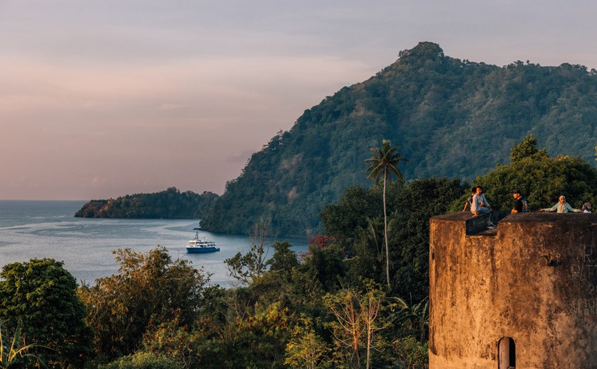 View of the Spice Islands with the Kudanil Explorer yacht anchored below, children watching the view from above during a private yacht expedition in Indonesia.