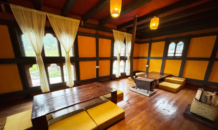 Traditional Rimphu Homestay interior with wooden flooring, low tables, and bright Bhutanese decor.